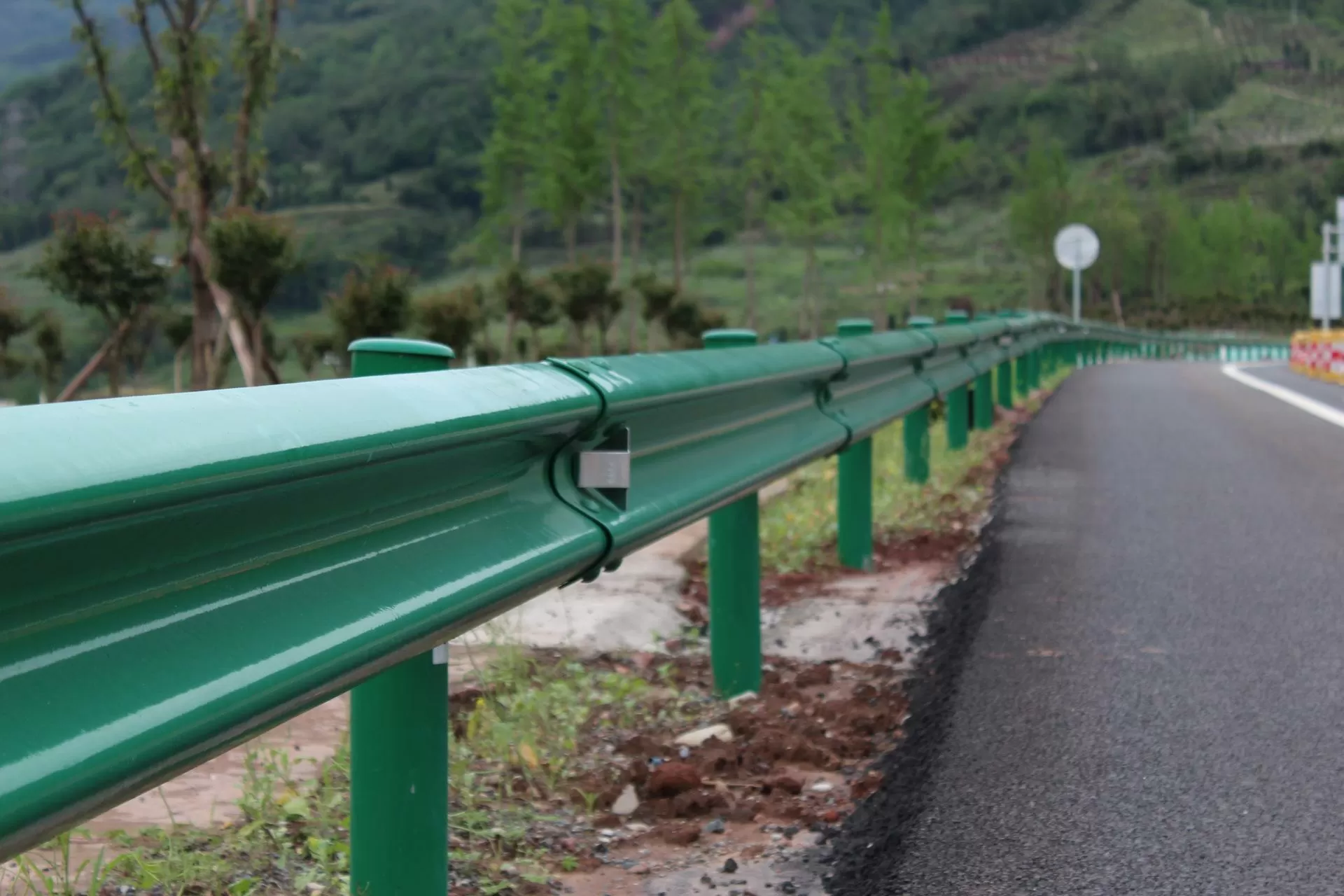 Corrugated W-beam steel road guardrail panels for a highway barrier
